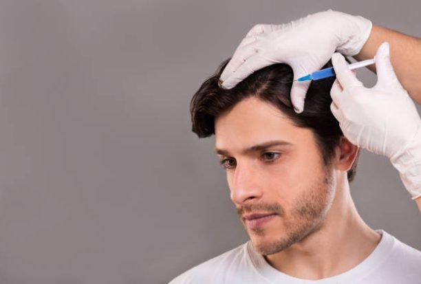 Man with hair loss problem receiving injection in head, grey background, empty space